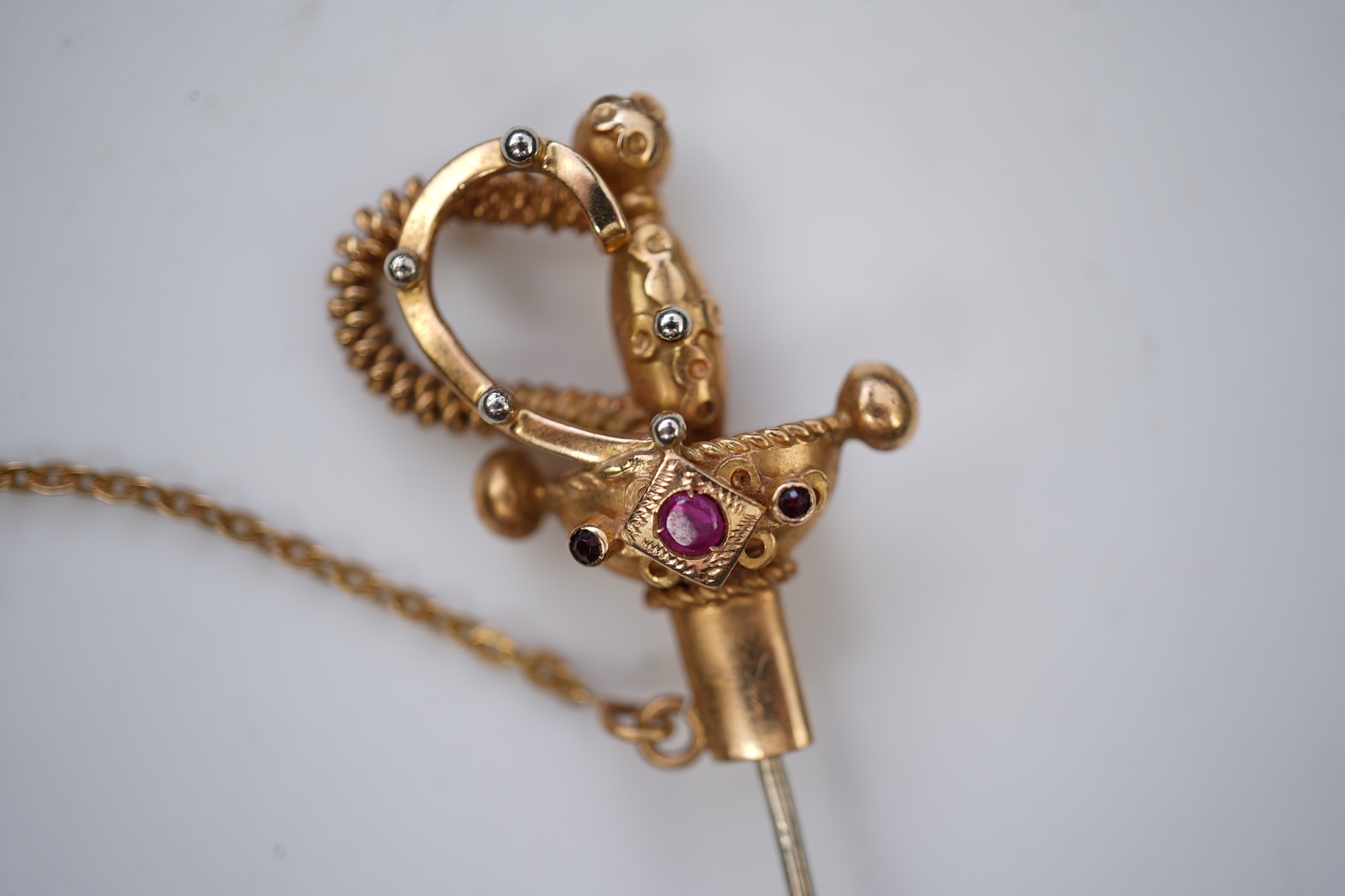 A gold and synthetic ruby jabot pin